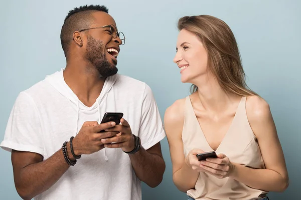 Felice coppia multietnica ridere utilizzando gli smartphone insieme — Foto Stock