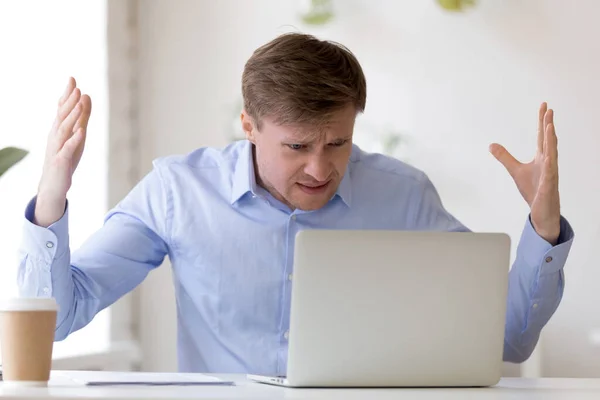 Homem de negócios de meia idade irritado olhando para a tela do laptop . — Fotografia de Stock