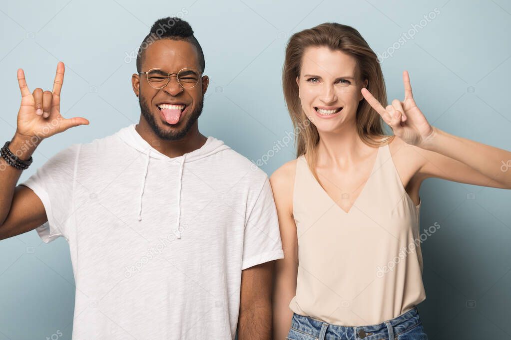 Excited multiethnic man and woman show rock-n-roll hand gesture