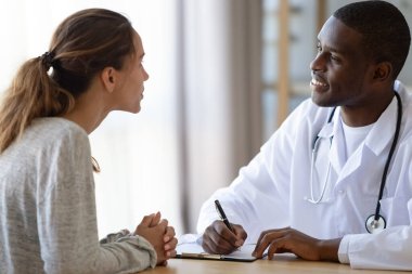 Afrikalı Amerikalı erkek doktor kadın hastaya danışmanlık yapıyor.