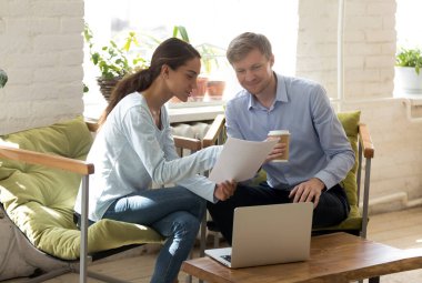 İş yerinde proje raporunu tartışan gülümseyen iki farklı meslektaşım.