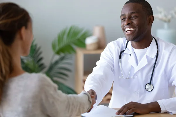 Sonriente afroamericano médico apretón de manos agradecida paciente femenina —  Fotos de Stock