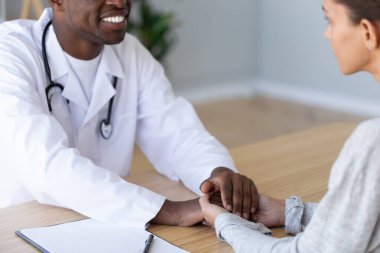 Bakımlı çift ırklı doktor sağlık kontrolünde hasta kadına destek gösteriyor.