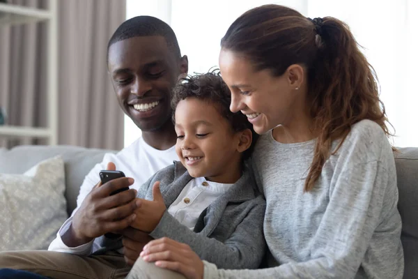 Oğlu evde cep telefonu kullanan mutlu çok ırklı ebeveynler. — Stok fotoğraf