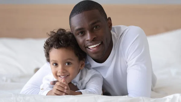 Portrait de heureux fils et père biracial couché sur le lit — Photo