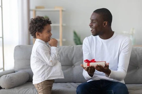 Little biracial boy present gift box to excited dad — Stock Photo, Image