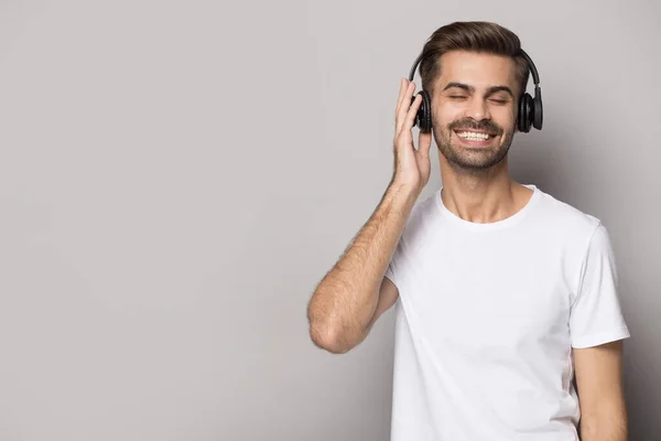 Homem caucasiano sorridente ouvir música em fones de ouvido modernos Bluetooth — Fotografia de Stock