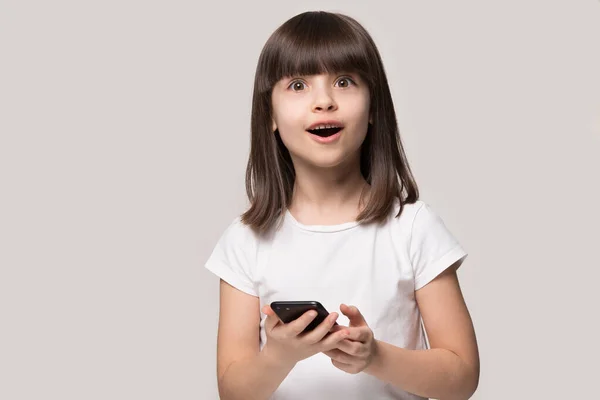 Surprised little girl shocked by smartphone online application — Stock Photo, Image