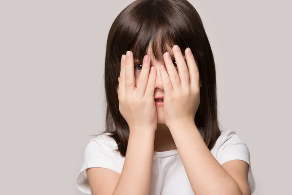 Испуганная маленькая девочка чувствует интерес подглядывать сквозь пальцы — стоковое фото