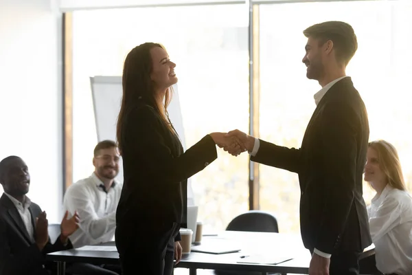 Happy proud female employee get promoted handshaking male boss manager