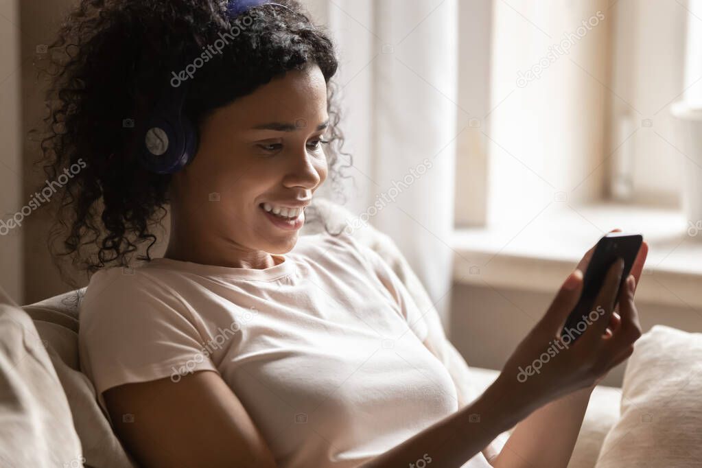 Happy african american woman in headphones using music mobile application.