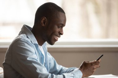 Gülümseyen Afrikalı etnik adam mobil uygulama kullanıyor, alışveriş yapıyor..