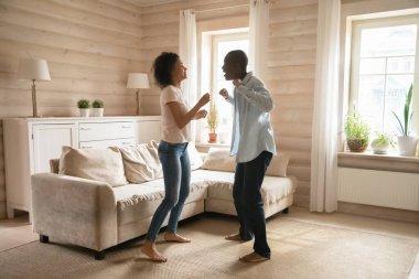 Neşeli melez aile eşi ahşap oturma odasında dans ediyor..