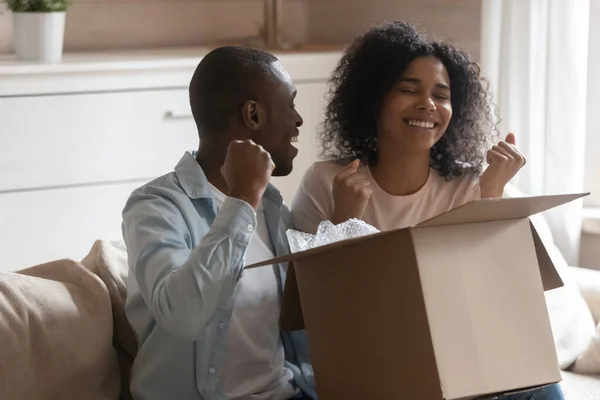 Happy millennial african american family couple unpacking long awaited parcel. — Stock Photo, Image
