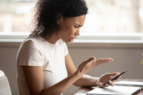 Angry african american young woman irritated by broken device.