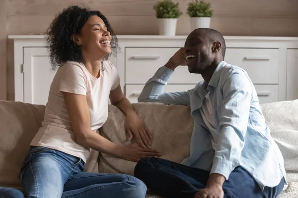 Alegre millennial africano americano casado pareja sentado en sofá, charlando . —  Fotos de Stock