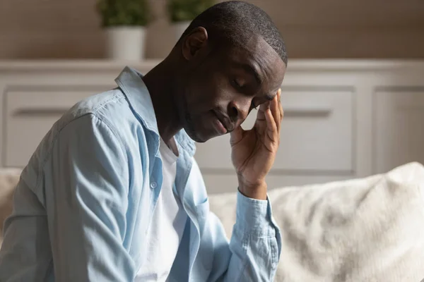 Uitgeputte jonge Afro-Amerikaanse man die last heeft van hoofdpijn, zich depressief voelen. — Stockfoto