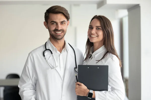 Usmívající se profesionálové mužský lékař a žena zdravotní sestra při pohledu do kamery — Stock fotografie