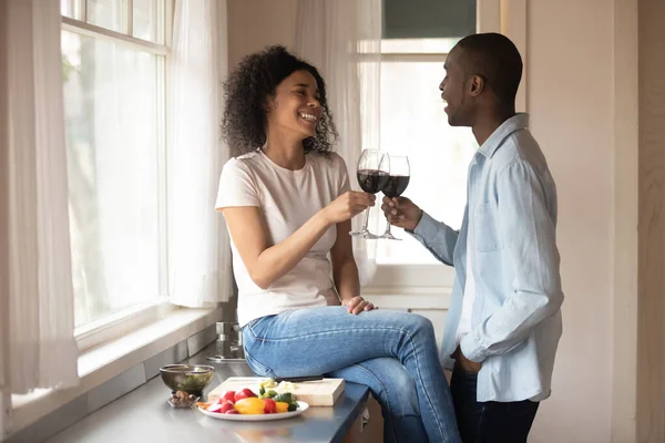 Joyful young black woman sitting on countertop, cheering with husband. — Stock Photo, Image