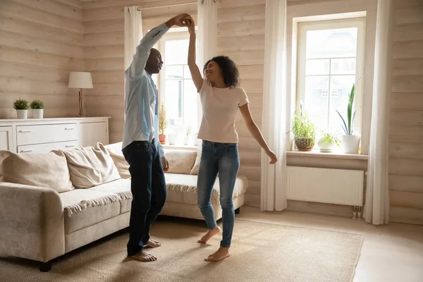 Щаслива змішана гонка подружня пара танцює, скручується на білому килимі . — стокове фото