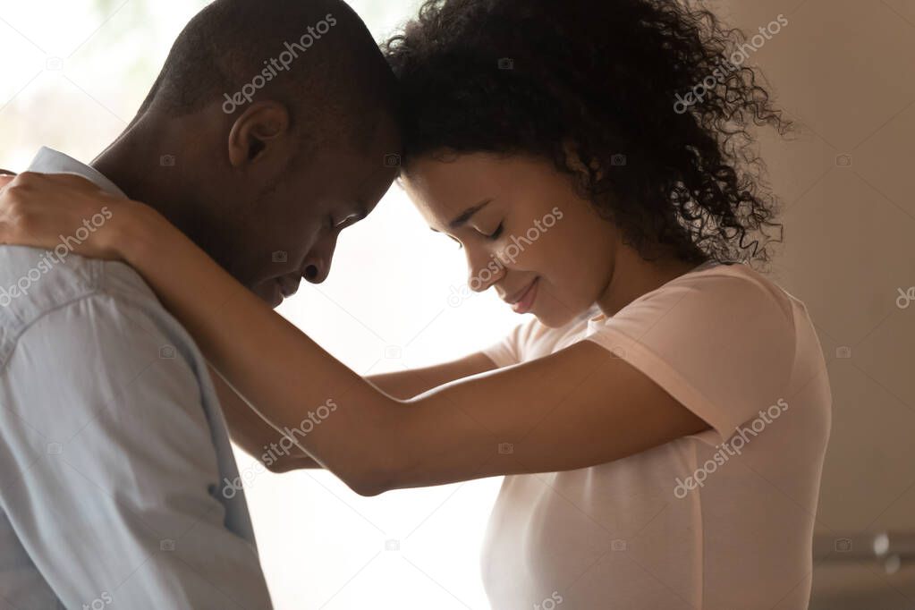 Side view happy african american woman cuddling beloved husband neck.