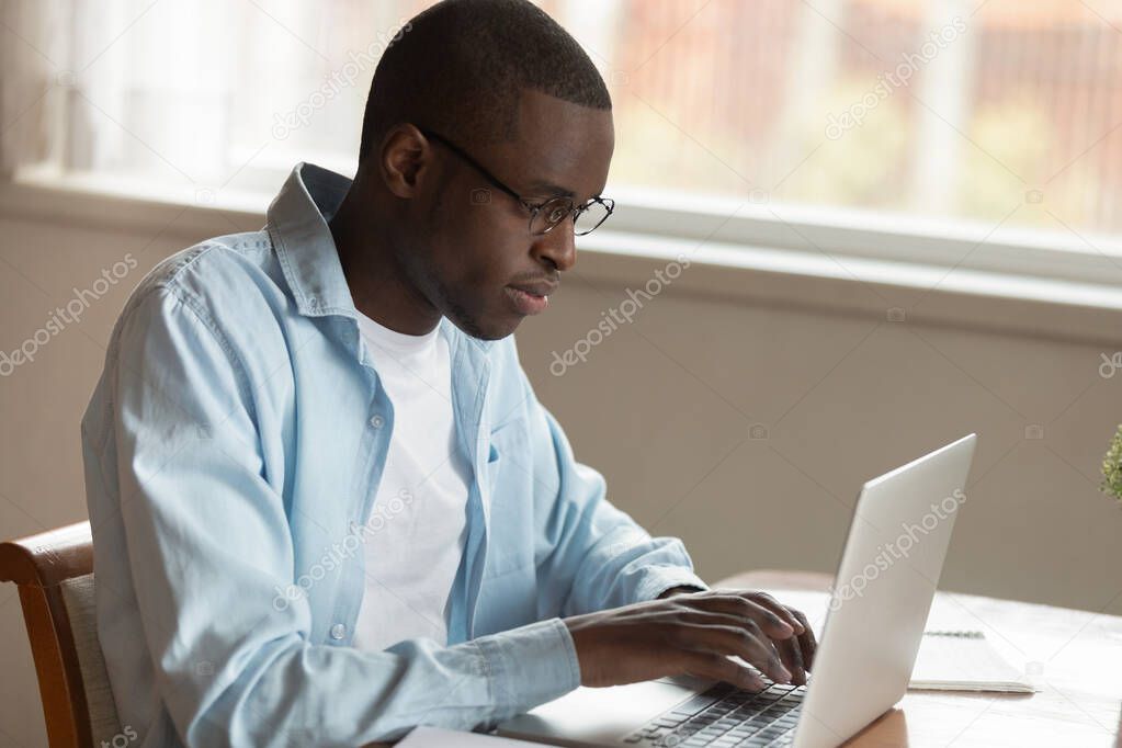 Serious concentrated young african american man working remotely with computer.