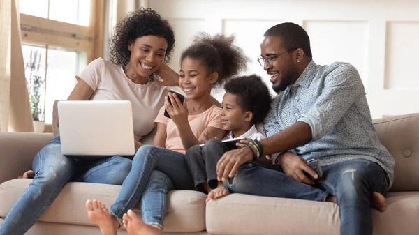 Smiling black family watch funny video on smartphone — ストック写真