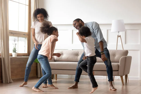 Happy black family with kids dancing together in living room — Stok fotoğraf
