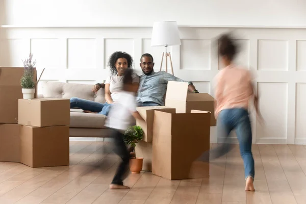 Los padres jóvenes ven a los niños pequeños correr en el día de mudanza — Foto de Stock