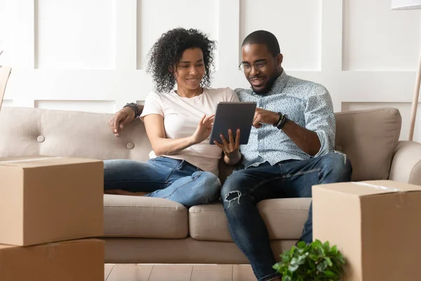 Black couple relax on couch with tablet on moving day — Stock Photo, Image