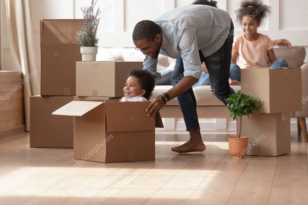 Happy black dad playing with small son on moving day