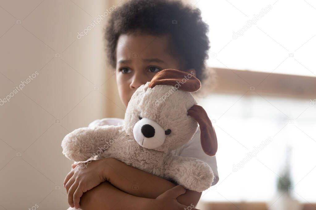 Hurt small biracial boy hold toy feeling lonely