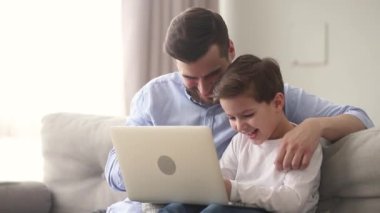 Baba ve küçük oğlu internetteki komik videolara gülüyorlar.