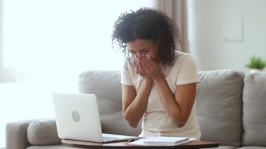 Afrikalı serbest çalışan kadın laptopta çalışırken hapşırıyor.