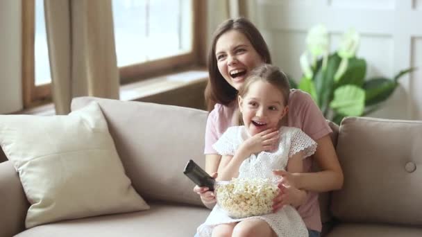 Mama i córeczka jedzą popcorn śmiejąc się w komedii — Wideo stockowe