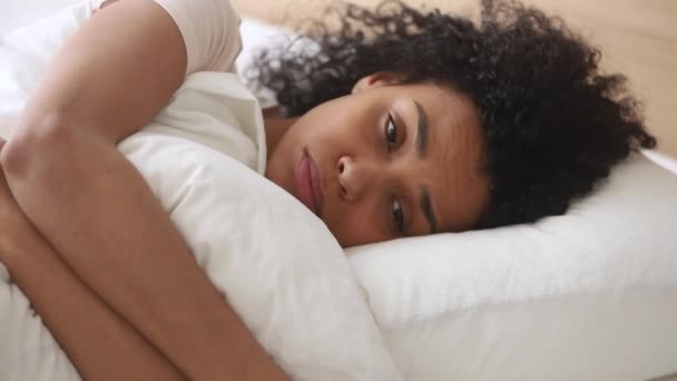 Deprimida mujer africana acostada en la cama abraza almohada se siente infeliz — Vídeos de Stock