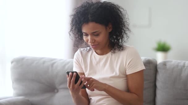 Riendo mujer africana sosteniendo teléfono inteligente leer anécdota se siente muy feliz — Vídeos de Stock