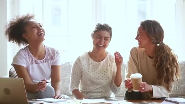 Skrattande multiracial studenter flickor njuta av att studera tillsammans sitter på soffan — Stockvideo