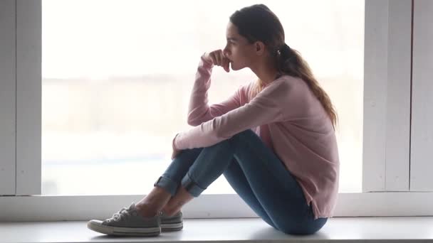 Pensive trieste vrouw zitten op vensterbank kijkt weg en denken — Stockvideo