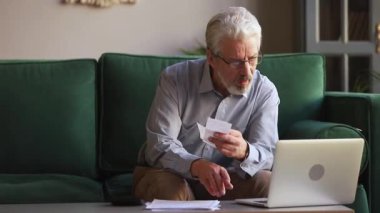 Yaşlı adam harcamaları hesaplayan hesap makinesi kullanarak kişisel bütçeyi yönetir