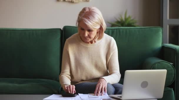 Пожилая европейская женщина с чеками подсчитывает счета чувствует беспокойство — стоковое видео