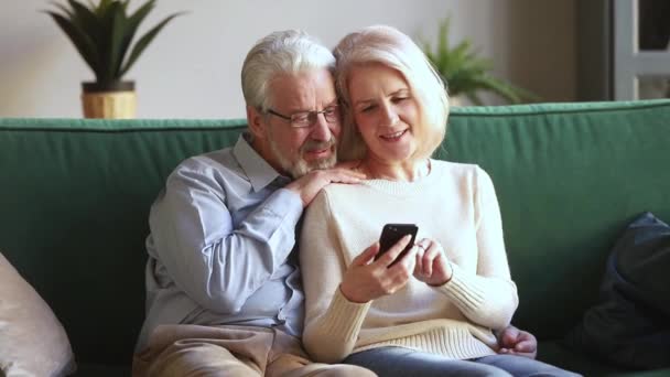 Stará žena a manžel sedí na gauči pomocí aplikací smartphone — Stock video