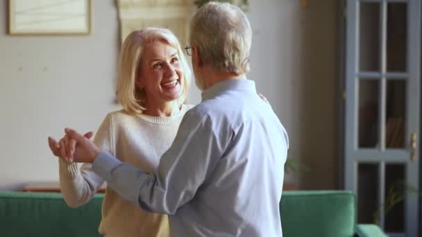 Пожилые супруги разговаривают танцуя вальс в гостиной — стоковое видео