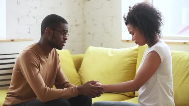 Африканский муж поддерживает грустную жену, сидящую на диване — стоковое видео