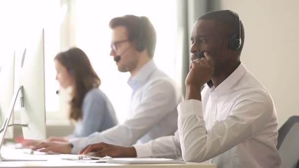 Trabajador del centro de llamadas masculino africano con auriculares ayuda al cliente distante — Vídeo de stock