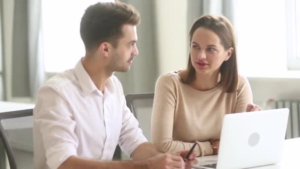 Miembros de la empresa discuten tarea común sentado cerca de la computadora portátil en el lugar de trabajo — Vídeo de stock