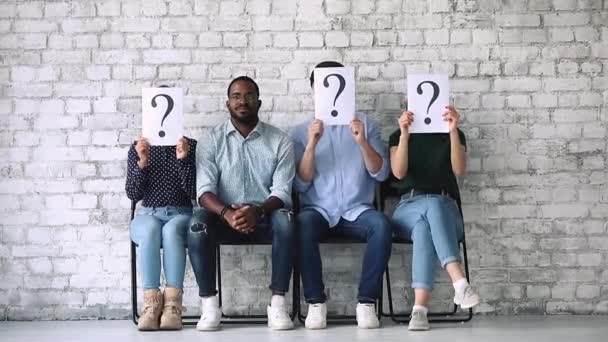 Jonge zwarte baan aanvrager zittend op stoel onder onbekende kandidaten. — Stockvideo
