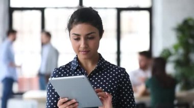 Ofiste dijital bilgisayar tableti kullanan genç Hintli bayan yönetici.