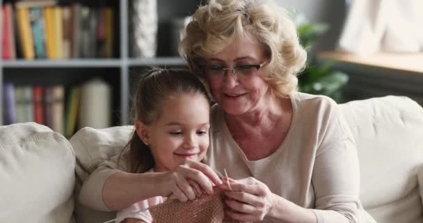 Šťastná babička ukazuje malou roztomilou vnučku, jak plést svetr. — Stock video