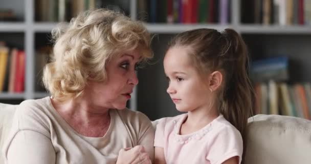 Sonriendo madura jubilada mujer charlando con un niño pequeño niña . — Vídeos de Stock